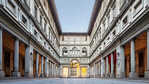 Ein geräumiger Innenhof mit klassischer Architektur, mit einem zentralen Bogen und Säulen an jeder Seite.