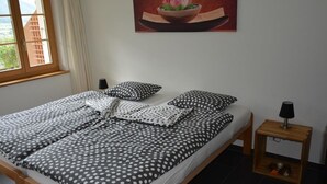Une chambre à coucher avec un lit, des oreillers, une table de chevet, un tableau et une fenêtre.