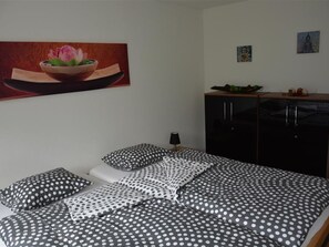 A bedroom with a bed, pillows, a nightstand, a lamp, a wardrobe, and a painting on the wall. - Bijou Eggetli Appartement/Fewo, Dusche oder Bad, WC 2-Bettwohnung by Interhome (Zweisimmen)