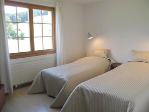 Ein Zimmer mit zwei Betten, einem Fenster und einem Nachttisch mit Lampe.