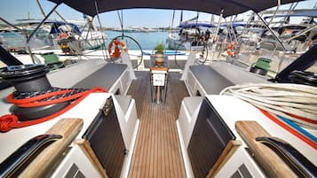 A boat deck with a steering wheel, life preserver, and ropes.