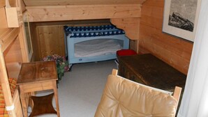 A small, cozy room with a wooden bunk bed, a small table, a chair, and a framed picture on the wall.
