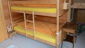 A bunk bed with a small chair and a table in a wooden room.