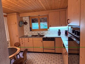A compact kitchen with wooden cabinets, a window, and a dishwasher.