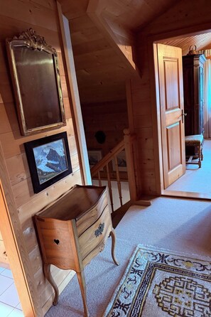 A wooden interior with a staircase, a wooden bench, and a wall-mounted mirror.