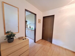 Ein Flur mit einem Holzkommode, einer Topfpflanze und einem gerahmten Bild an der Wand.