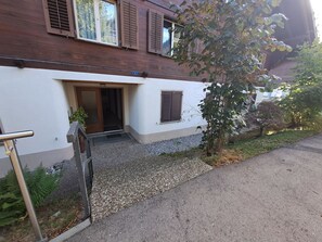 Ein Gebäude mit weißer Fassade, einer Holztür und einem Kiesweg, der zum Eingang führt.