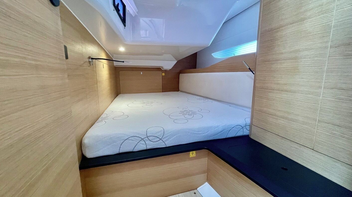 A compact, well-lit interior with a bed, wooden walls, and a ceiling with a skylight.