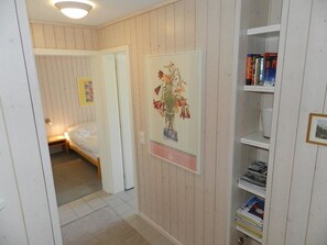 A bedroom with a bed, a bedside table, a nightstand, a wall-mounted shelf with books, and a framed picture of flowers. - Suzanne Nr. 20 Appartement/Fewo, Dusche oder Bad, WC 5-Bettwohnung by Interhome (Gstaad)