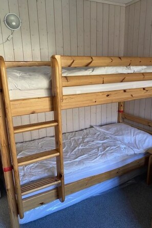 Een stapelbed met houten frame en een ladder, een wandlamp en een vloer bedekt met blauw tapijt.