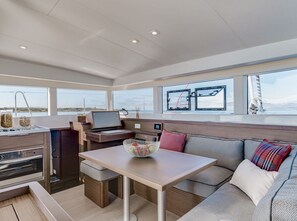 A modern galley with a stove, a laptop, and a dining area with a table and sofa. - Sun-Kissed Sailing Adventure in the Sporades Islands from Volos, Thessaly (Volos)