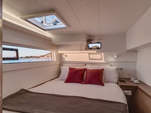 Una camera da letto con un letto, una finestra, una piccola TV e un comodino.