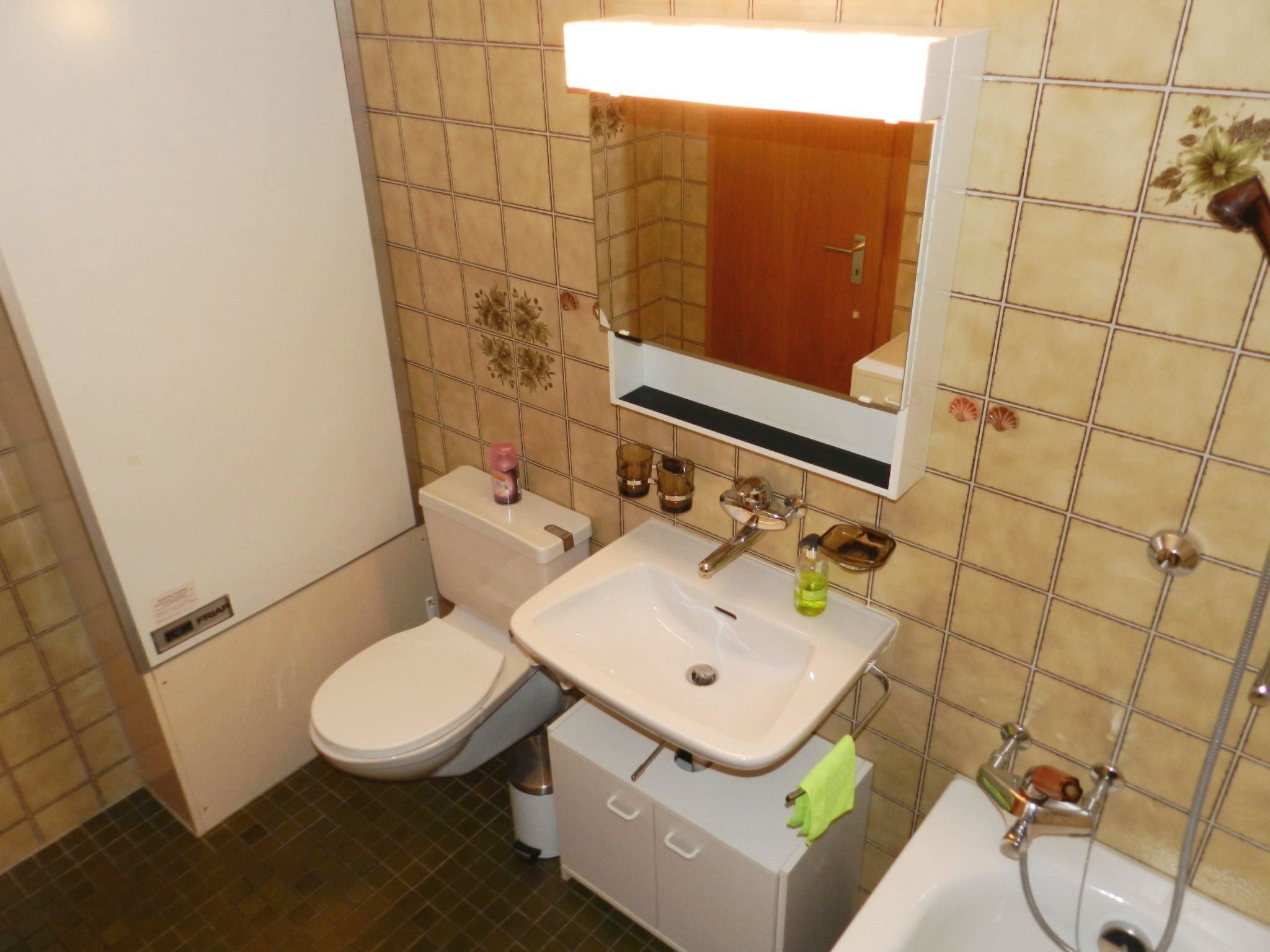 A bathroom with a toilet, sink, mirror, and shower.