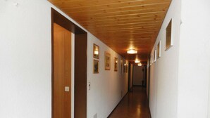 Ein Flur mit Holzboden, weißen Wänden und gerahmten Bildern.