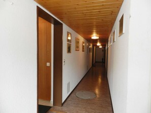 Um corredor com teto de madeira, paredes brancas e quadros emoldurados.