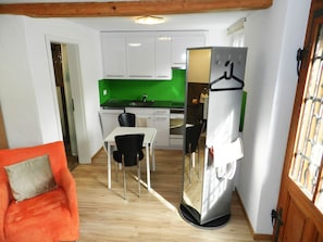 A compact kitchen with white cabinets, a green backsplash, and a stainless steel refrigerator with a hanging rack. - Studio Etana Studio, Dusche oder Bad, WC 2-Bettwohnung by Interhome (Zweisimmen)