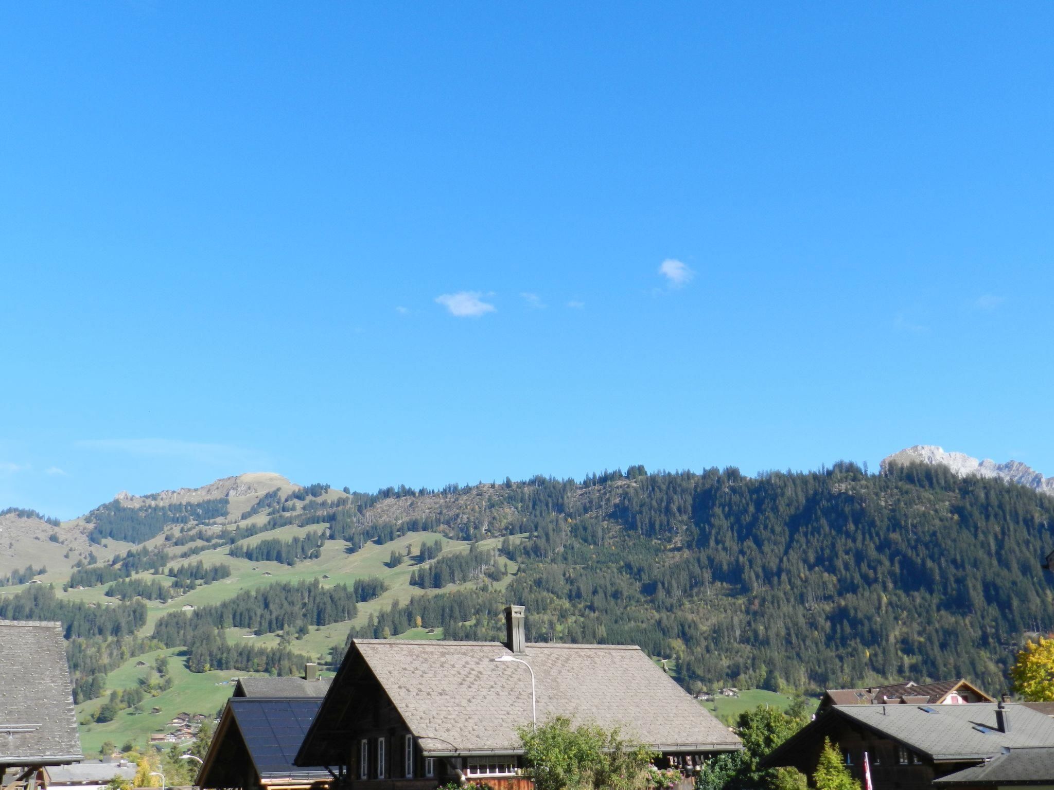 Un pueblo de montaña con casas de madera tradicionales, cielo despejado y una ladera boscosa.