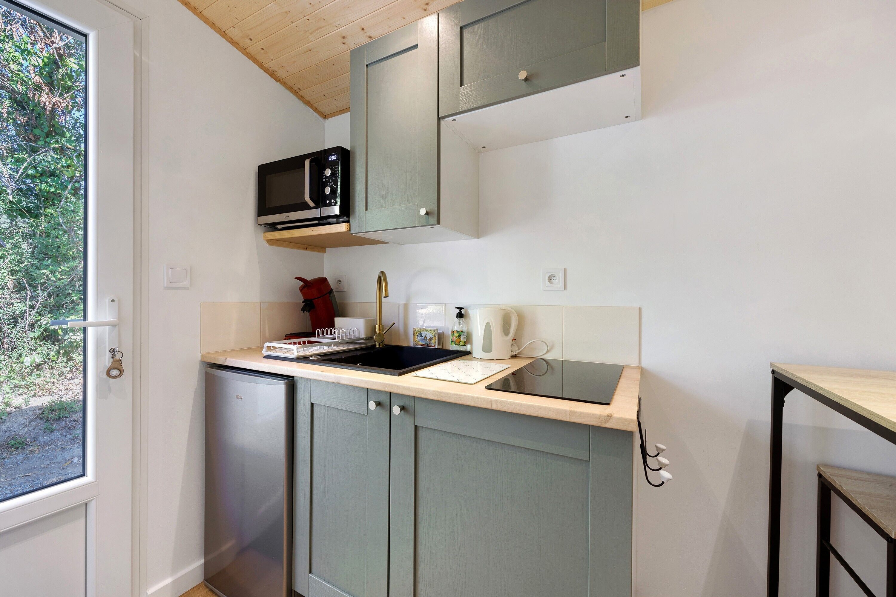 A compact kitchen with a microwave, sink, and a small refrigerator.