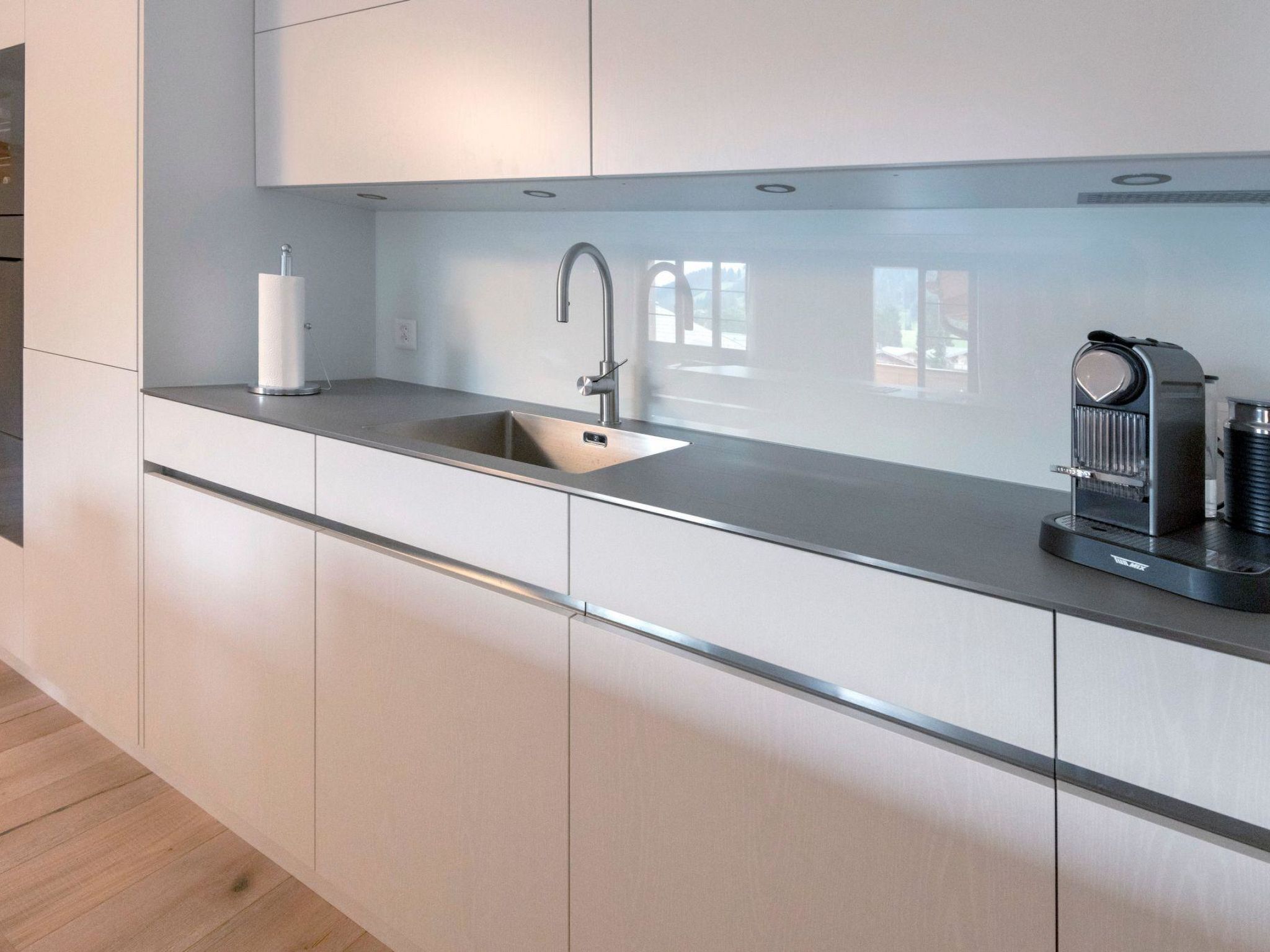 Una cucina moderna con lavello in acciaio inossidabile, un rubinetto e una macchina per il caffè.