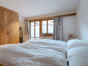 Une chambre à coucher avec un grand lit, une armoire en bois et une fenêtre avec des rideaux.