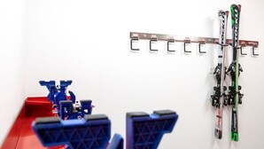 Un portaequipajes de esquí con esquíes y bastones, un banco rojo y un asiento de telesilla azul.