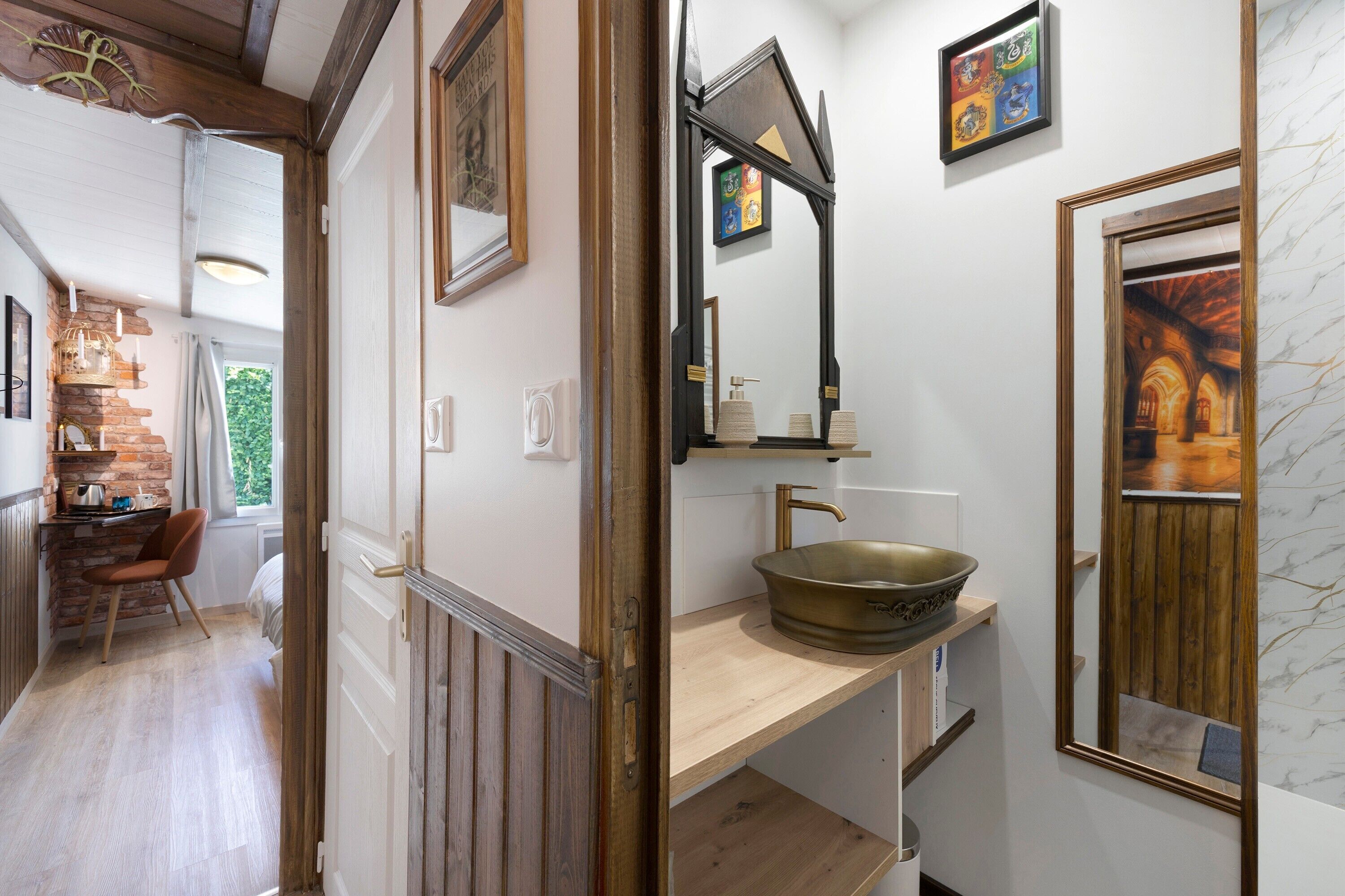 A hallway with a wooden floor, a sink with a bowl, a mirror, and a framed picture on the wall.