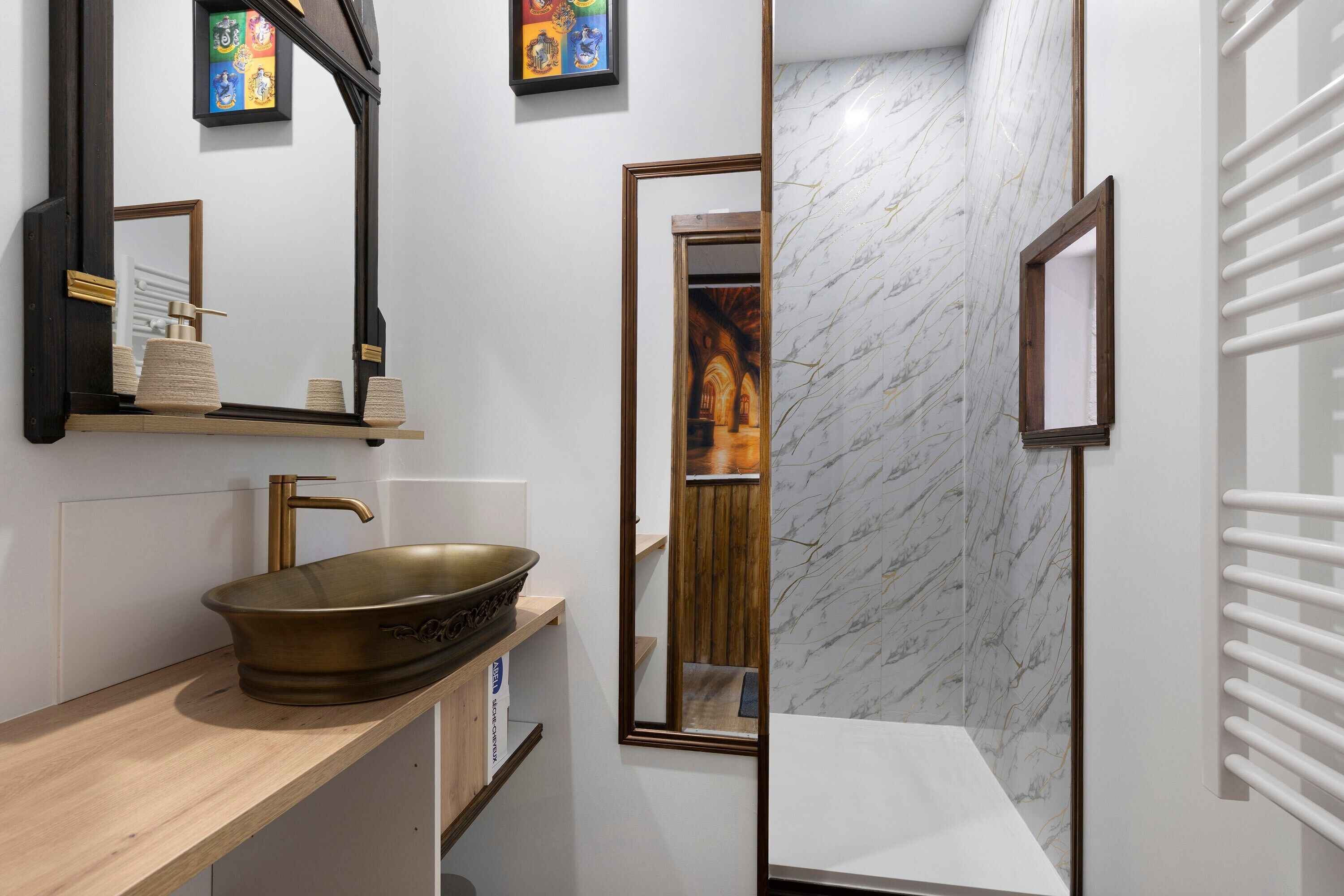 A bathroom with a large mirror, a vessel sink, and a marble wall.