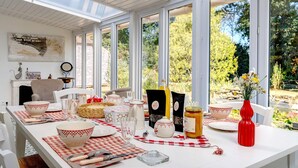 A dining area with a table set for a meal, surrounded by large windows, and a view of the outdoors. - Guest Room "Le Cocon du Sorcier" in the Marais Breton Vendéen, 25 min from Noirmoutier (Châteauneuf)