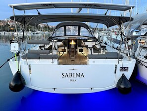 A boat named 'Sabina' with a cabin area, a steering wheel, and a brand name 'EOL YACHTING' on the side.