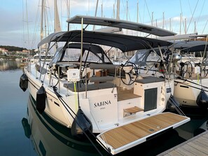 A Sabina Pula yacht docked at a marina with multiple masts in the background.