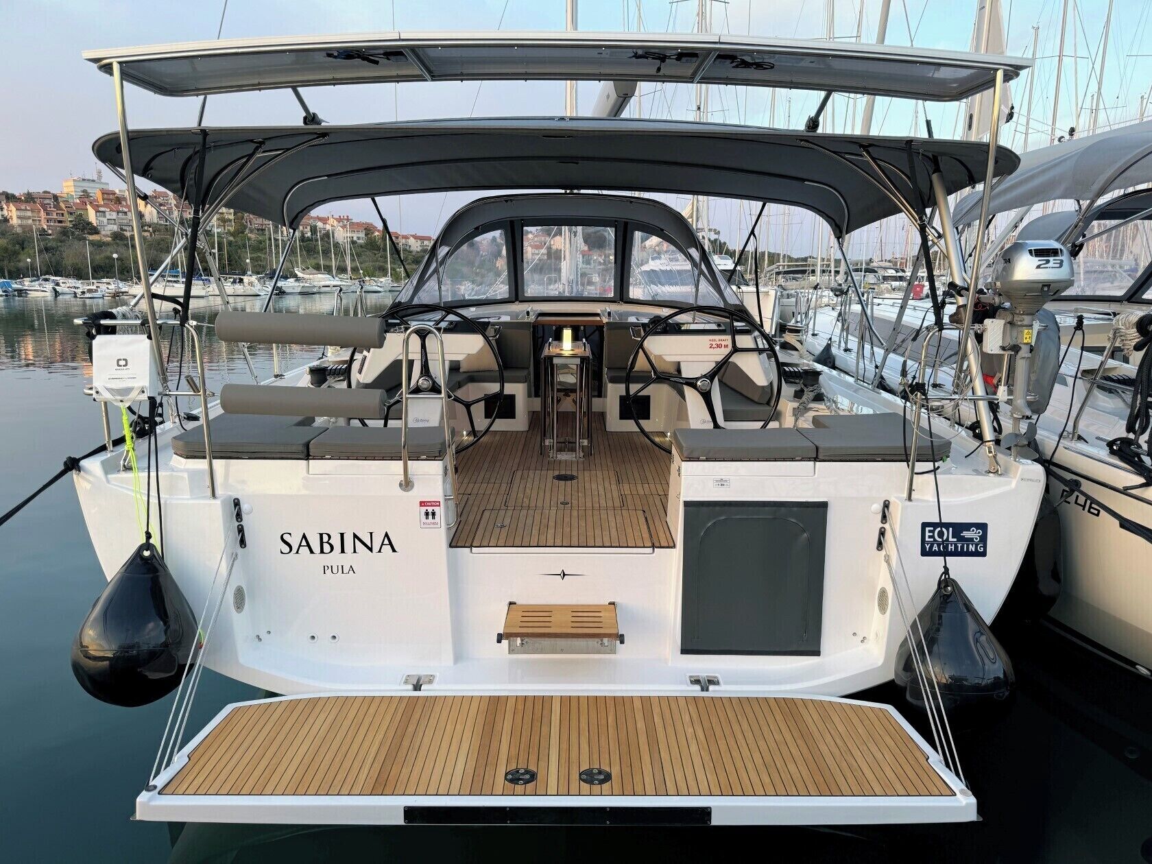 Eine Yacht namens 'Sabina' mit einer überdachten Deckfläche, einem Steuerrad und einem Sitzbereich.