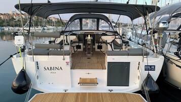 Eine Yacht namens 'Sabina' mit einer überdachten Deckfläche, einem Steuerrad und einem Sitzbereich.