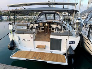 A boat named 'Sabina Pula' docked at a marina with a covered deck area, a steering wheel, and a small seating area.