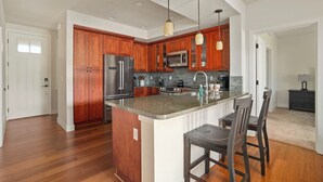 Una cocina moderna con armarios de madera, electrodomésticos de acero inoxidable y una isla central con taburetes de bar.