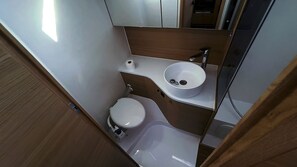 A compact bathroom with a toilet, sink, and mirror. - Sibenik Sun-soaked Sailing: A Luxurious Croatian Voyage (Pirovac)