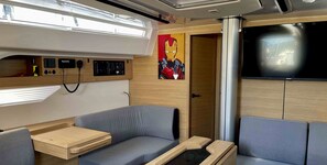 A modern RV interior with a sofa, a small table, a control panel, and a TV mounted on the wall. - Sibenik Sun-soaked Sailing: A Luxurious Croatian Voyage (Pirovac)