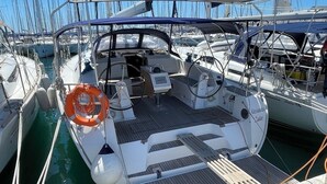 Un port de plaisance où sont amarrés de nombreux voiliers, avec un cockpit équipé d’un volant, d’une bouée de sauvetage et d’un panneau de commande.