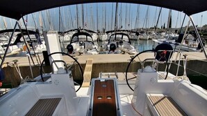 Un puerto deportivo con varias embarcaciones amarradas, un paseo central y una zona cubierta con asientos.
