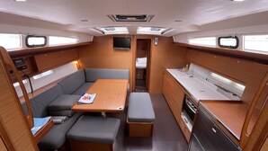 Un espacio interior compacto con kitchenette, zona de estar y un televisor pequeño.