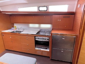 Eine kleine Küchenzeile mit Spüle, Herd, Backofen und Kühlschrank.