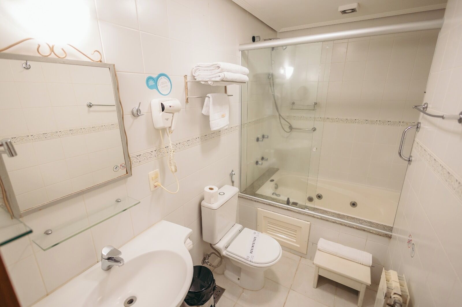 A bathroom with a glass-enclosed shower, a toilet, a sink, and a mirror.