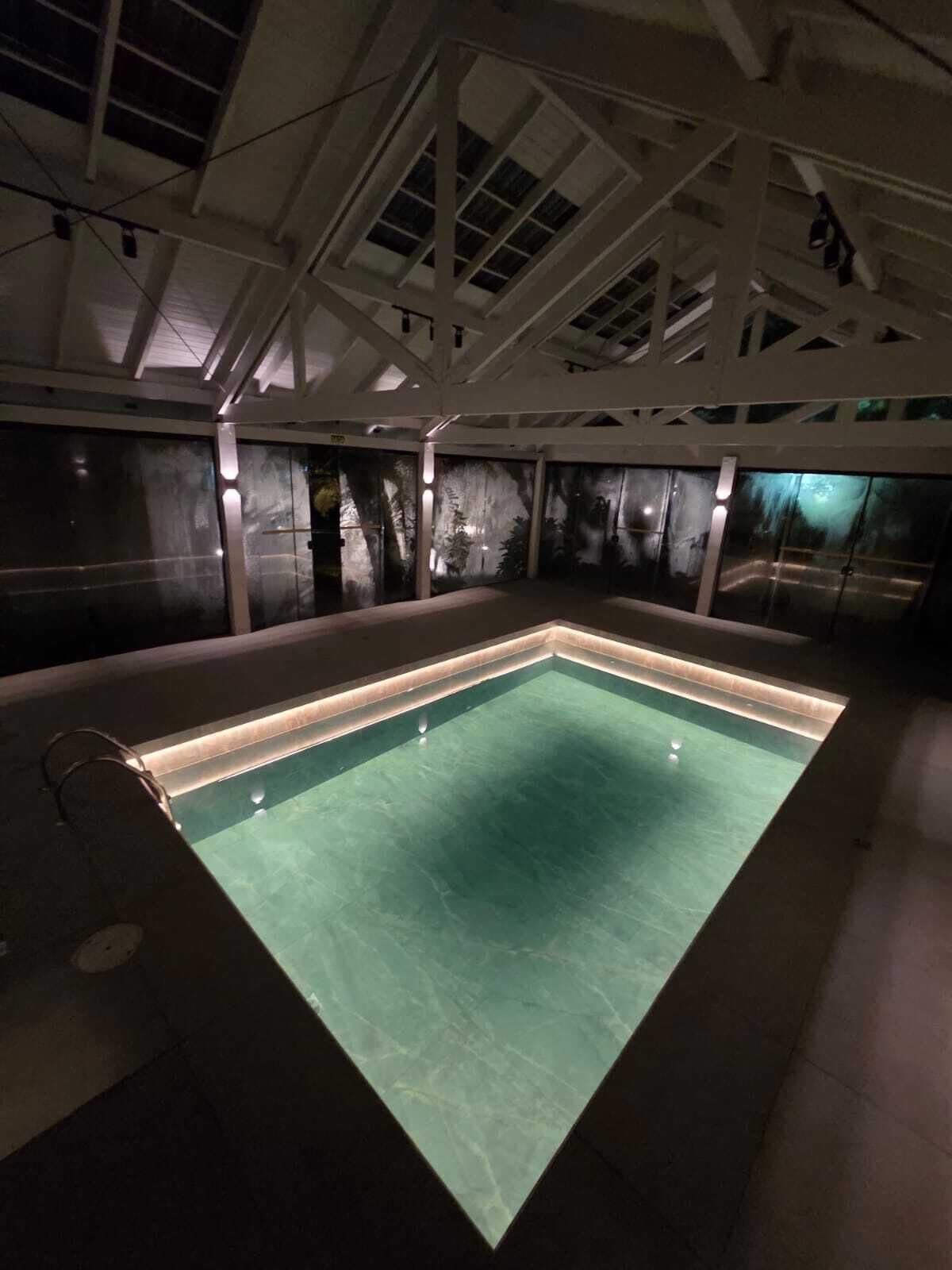 An indoor swimming pool with a clear view of the ceiling structure and walls.