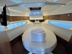 A modern, well-lit interior with a central bed, two side seating areas, and a television. - Sun-Kissed Sailing Adventure in Zadar, Croatia (Bibinje)