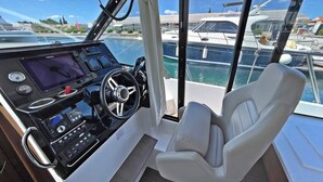 A boat's control station with a steering wheel, navigation screen, and a single white leather seat. - Sun-Kissed Sailing Adventure in Zadar, Croatia (Bibinje)