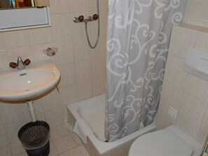 A bathroom with a white sink, a shower curtain, and a toilet.