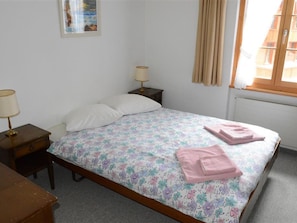A bedroom with a single bed, two bedside tables, a nightstand, a window with curtains, and a wall-mounted picture. - Mireille Nr. 6 Appartement/Fewo, Dusche oder Bad, WC 2-Bettwohnung by Interhome (Gstaad)