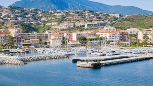 Un port de plaisance avec des bateaux, une jetée et des bâtiments, le tout surmonté d’un paysage montagneux.