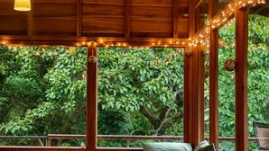 A wooden cabin with a built-in bench and a view of lush greenery. - El Refugio La Brisa del Diablo – Jungle House (Letrero,)