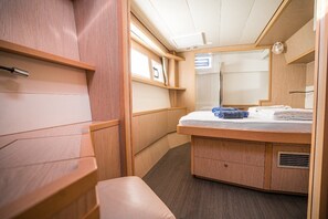 A compact, well-lit cabin with a wooden vanity, a mirror, a bed, and a bench. - Sibenik Sun-soaked Sailing: A Luxurious Croatian Voyage (Pirovac)
