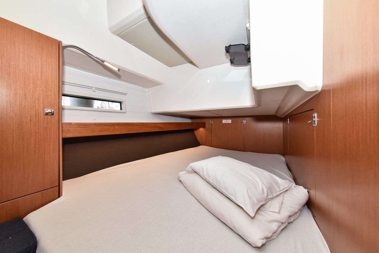 A compact cabin with a bed, a small window, and a sink.